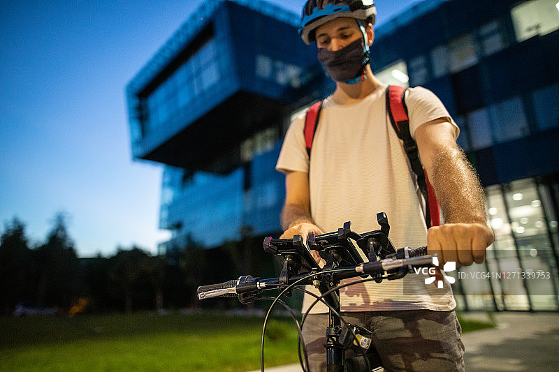 送餐员使用手机应用程序在自行车车把上的手机上寻找下一个顾客的位置图片素材