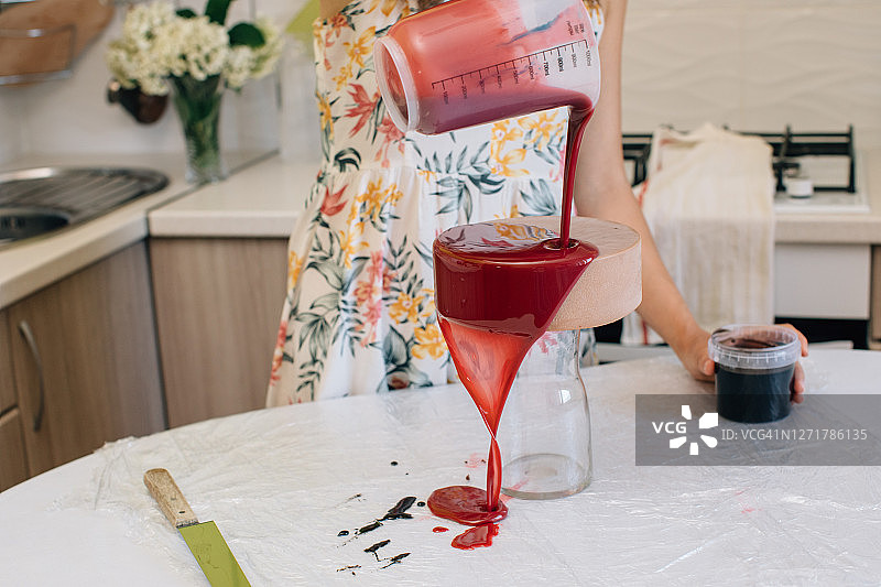 一名妇女在自制的红丝绒巧克力蛋糕上浇釉图片素材