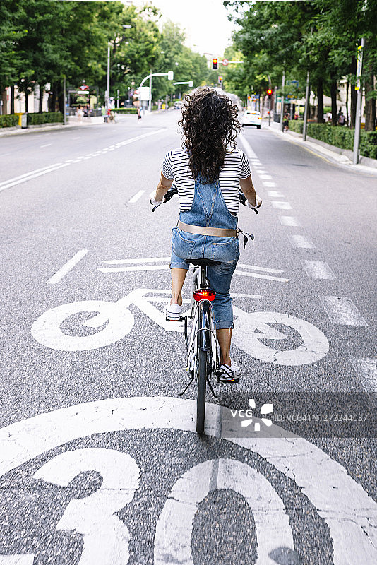 在城市的街道上骑电动自行车的妇女图片素材