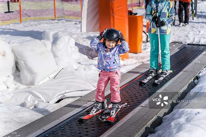 一个年轻的滑雪女孩在传送带上学习滑雪图片素材