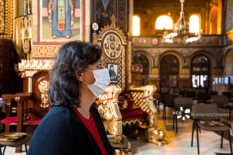 在天主教教堂祈祷的妇女戴着防护面具图片素材