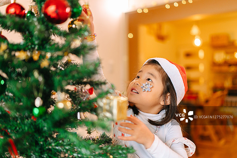 小女孩喜欢在家里的客厅里装饰圣诞树图片素材