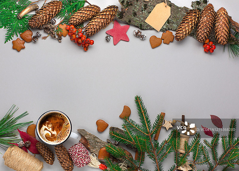 天然的圣诞装饰，咖啡杯，姜饼饼干，松果和树枝在灰色的纸背景。图片素材