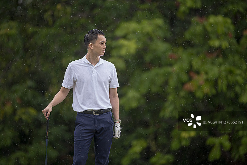 亚洲华人年轻男性高尔夫球手在高尔夫球场上拿着高尔夫球杆图片素材