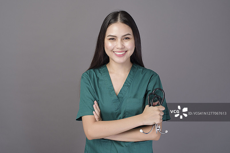 一个女医生穿着绿色的手术服和听诊器在灰色的背景演播室图片素材