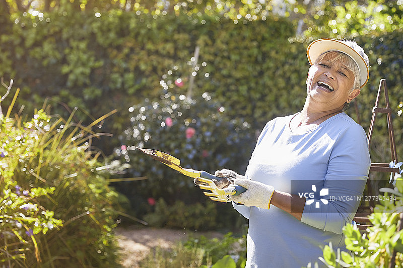 快乐的退休老妇人在后院园艺图片素材