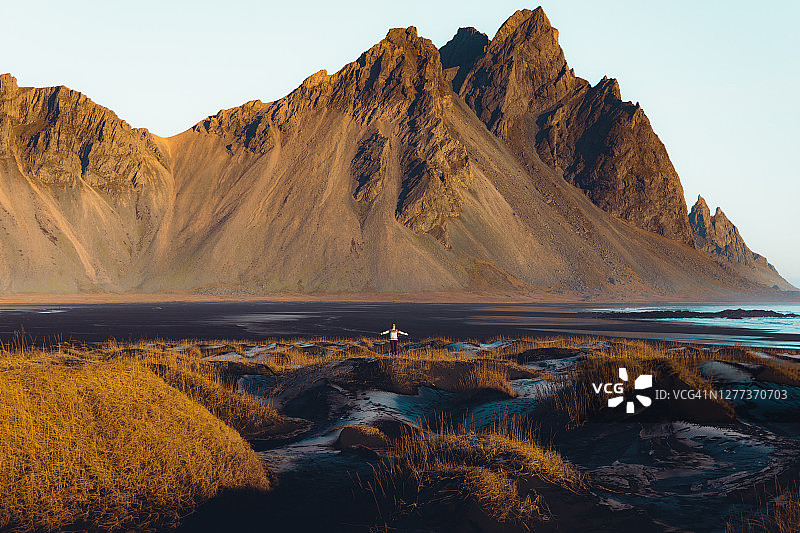 女人旅行者遇到日出减弱美丽的黑沙山海滩在冰岛图片素材