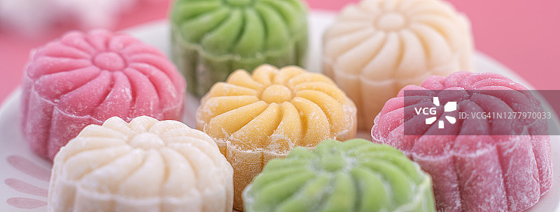 彩色的雪皮月饼，甜的雪月饼，传统美味的甜点中秋节在柔和的淡粉色的背景，近距离。图片素材