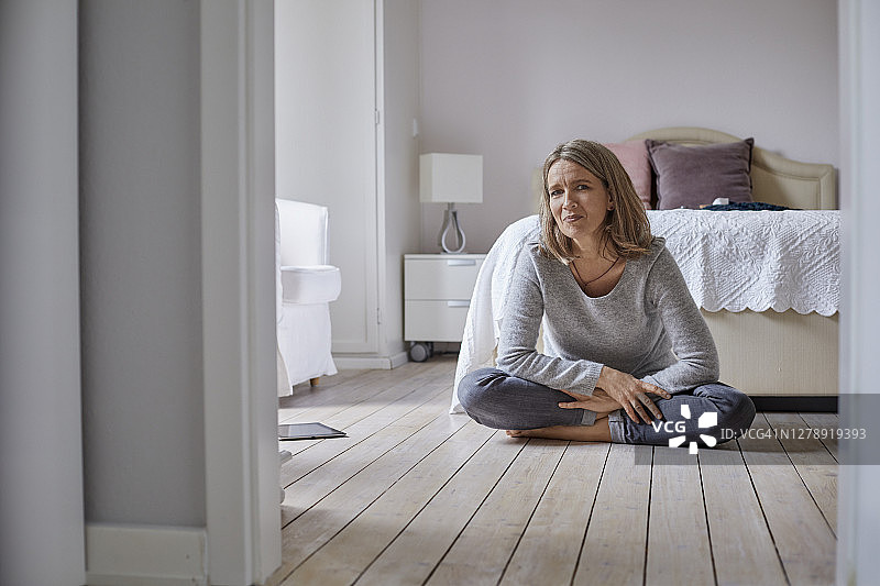 一个自信成熟的女人坐在家里地板上的肖像图片素材