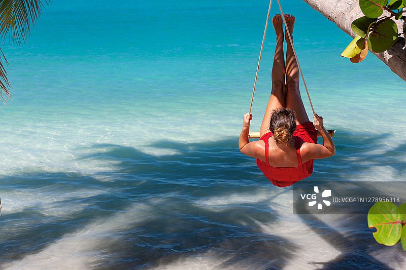 迷人的女人在加勒比海的热带海滩荡秋千图片素材