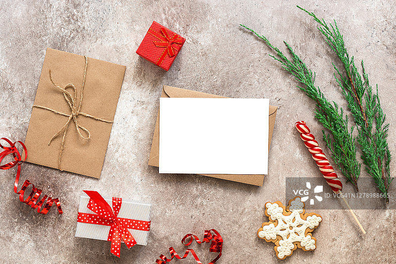 手工信封里的空白卡片。圣诞卡模型。冷杉枝，礼盒，棒棒糖，姜饼和蛇纹石在米色垃圾背景。俯视图，平放，复制空间。图片素材