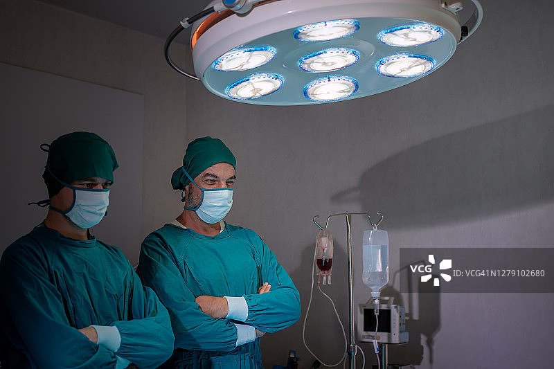 一组外科医生在黑暗的手术室里。图片素材