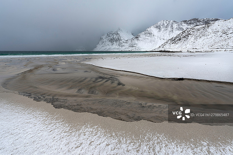 冬天在被雪覆盖的海滩上流向大海的小河图片素材