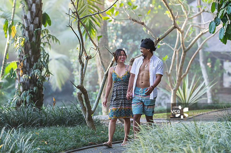 在热带度假胜地的丛林景观中漫步的幸福情侣图片素材