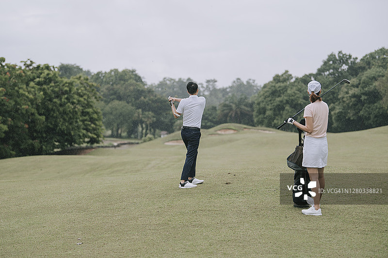 亚洲华人男子高尔夫球手在高尔夫球场上挥杆开球图片素材
