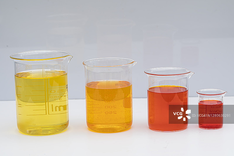 盛有彩色液体的烧杯。化学解决方案。实验室烧杯与有色液体在白色背景图片素材