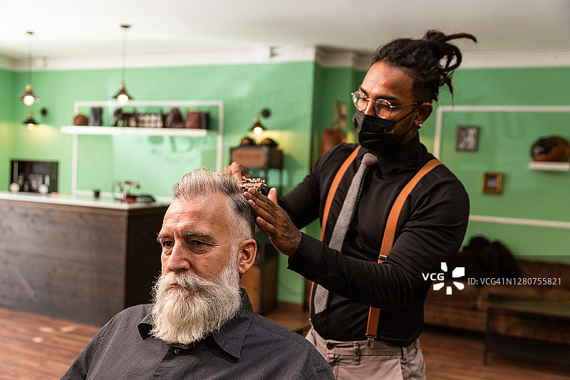 非裔美国理发师戴口罩，用梳子梳理白胡须的白人男性冠状病毒疫情预防图片素材