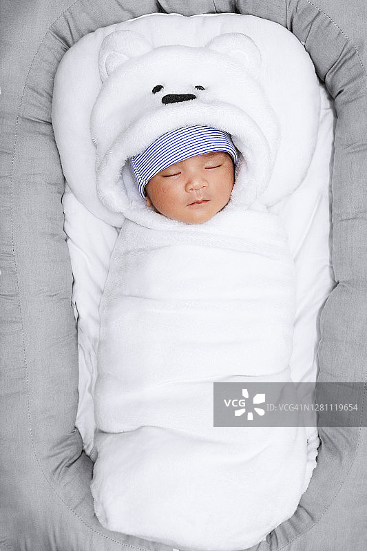 裹着白色毯子的新生儿。襁褓中的婴儿正在睡觉。图片素材