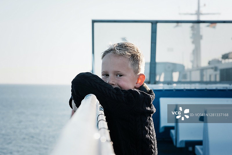 一个小男孩在渡船上的肖像，在海上看起来快乐和放松图片素材
