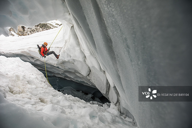 登山者用绳索滑入冰川裂缝中寻找迷路的徒步旅行者图片素材