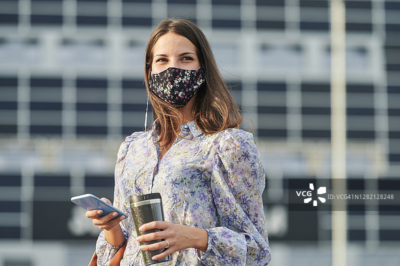 年轻女子戴着口罩在城市里使用手机图片素材