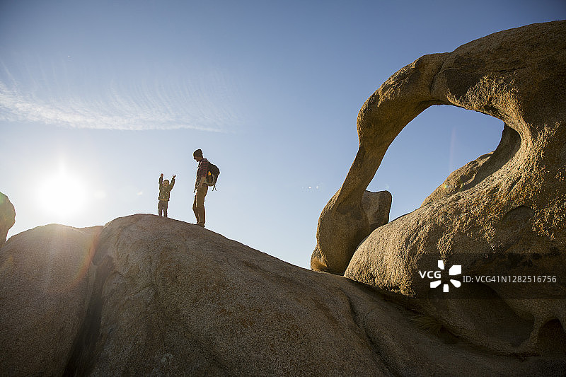 一个小男孩和他的父亲徒步在一个拱形的山中岩石小径的场景。图片素材