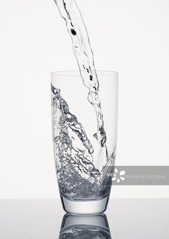水倒进白色背景的玻璃杯中图片素材
