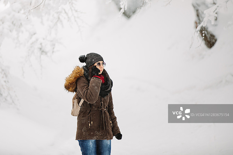 一个年轻的女人穿过雪山森林图片素材