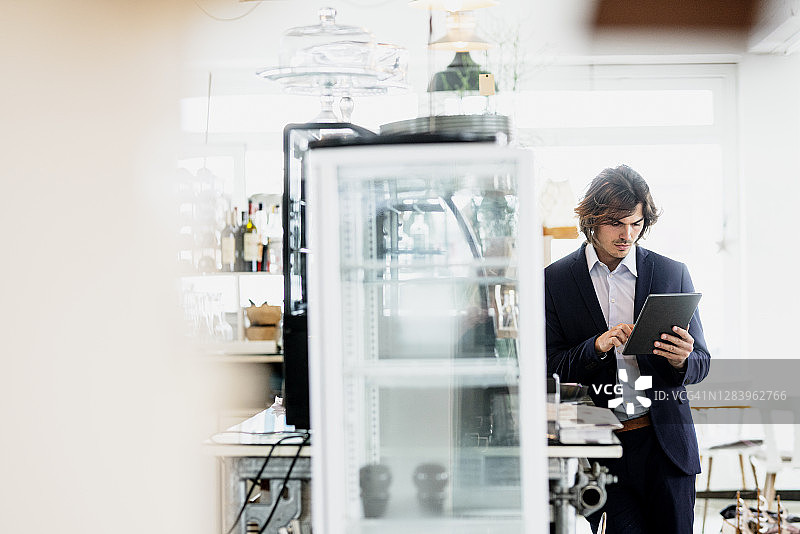男性企业家站在咖啡馆里使用平板电脑图片素材