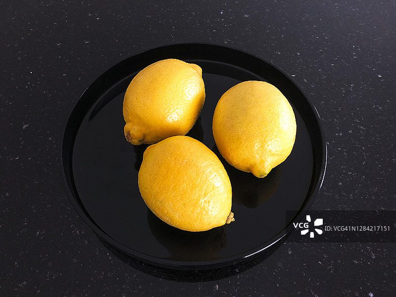 三个柠檬在一个黑色盘子里的特写图片素材