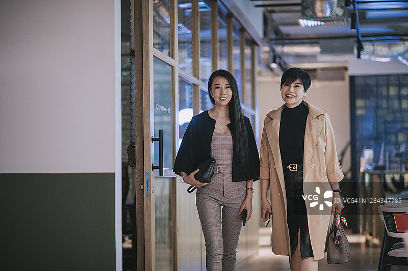 两位成功的亚洲华裔女商人高高兴兴地走进办公室图片素材