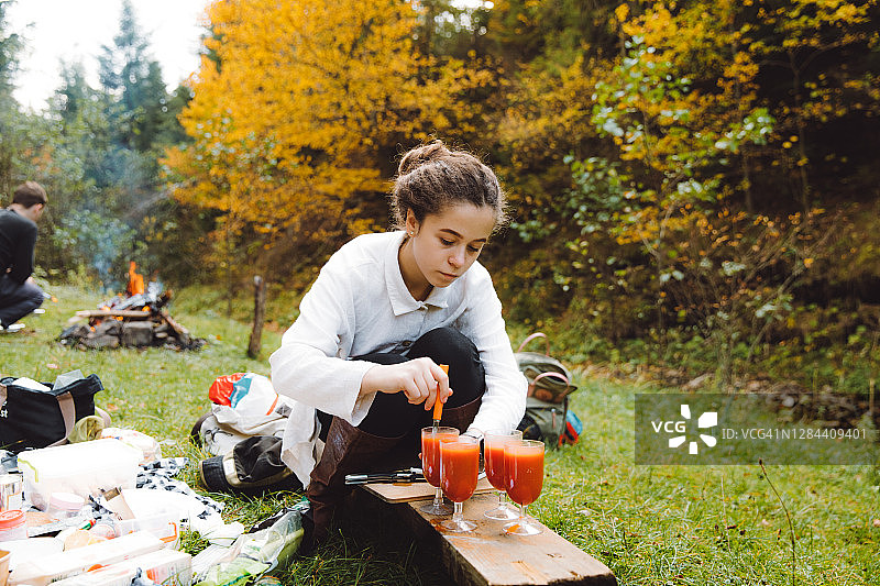 年轻女子准备野餐在美丽的森林和饮料图片素材