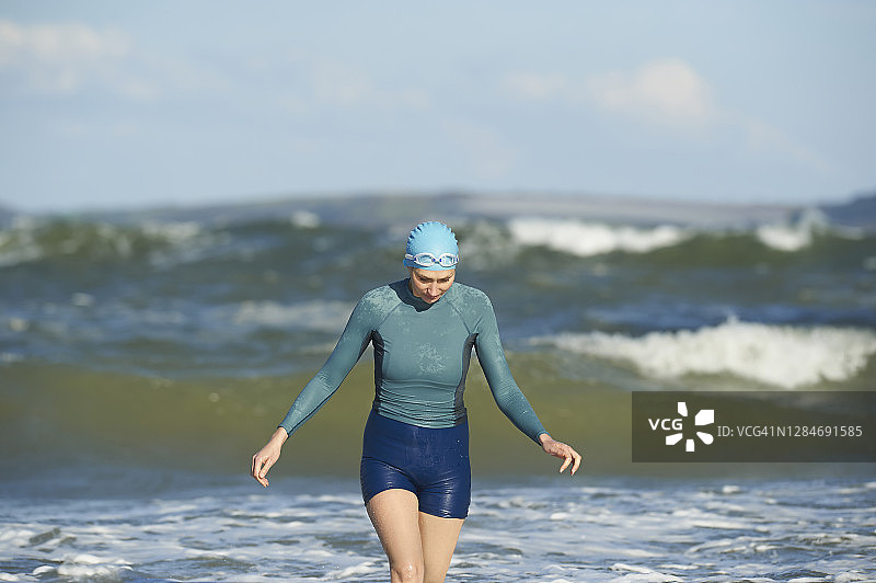 女人在海里游泳后走回海滩。图片素材