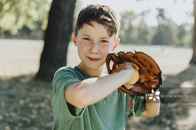 男孩戴着棒球手套站在公园里图片素材