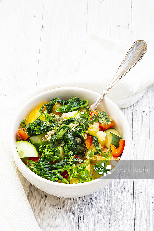 一碗由菠菜，甜椒，黄瓜，番茄，欧芹和薄荷组成的蔬菜沙拉图片素材