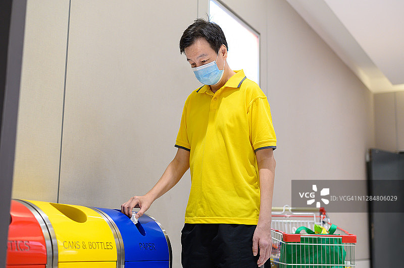 中亚成人将垃圾放入废物分类回收箱内图片素材