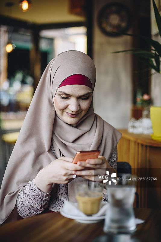 年轻的穆斯林妇女使用手机图片素材