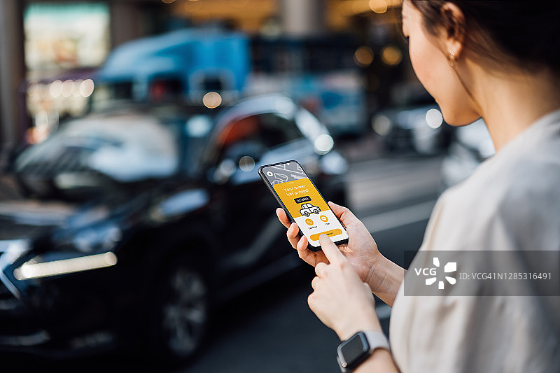 在这个城市里，年轻的亚洲女商人用智能手机上的移动应用设备安排出租车叫车服务。服务快捷可靠。众包和商业的概念图片素材