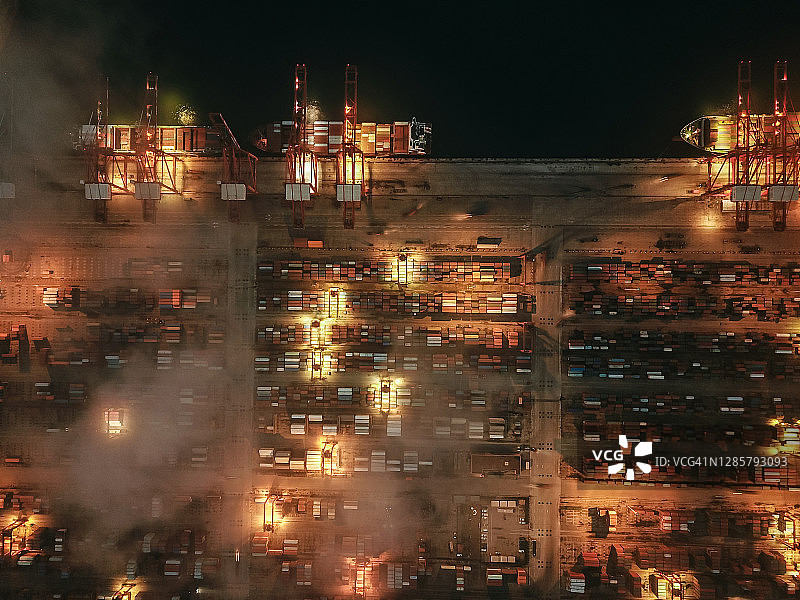 鸟瞰图繁忙的工业港口与集装箱船在夜间图片素材