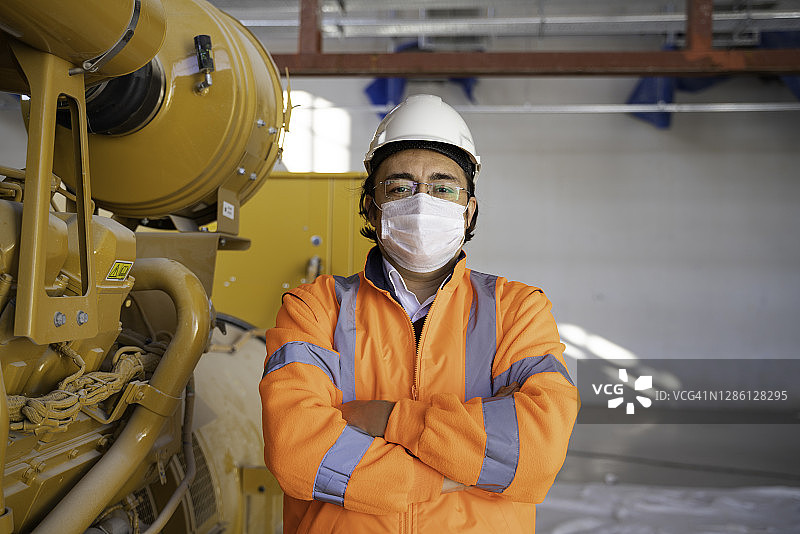 值班的男工程师穿着防护服站在工厂使用的机器前微笑图片素材