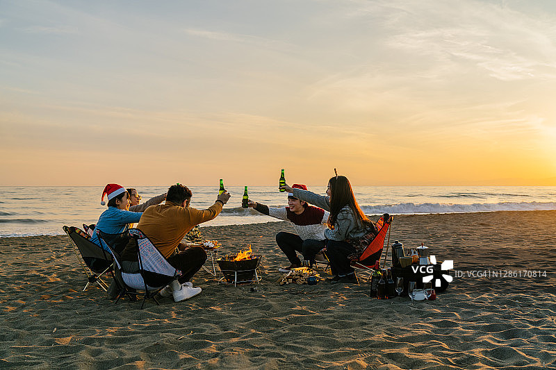一群年轻的朋友在日落时分的海滩上庆祝圣诞节图片素材