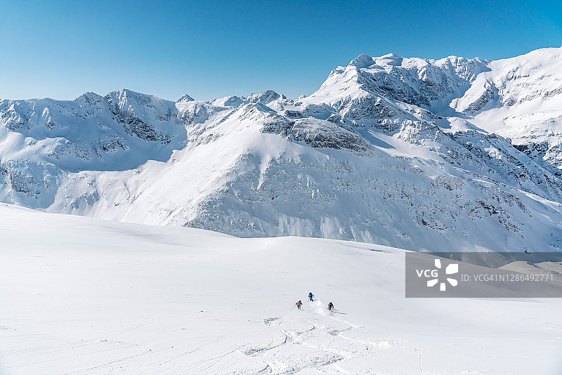 鸟瞰图三个人滑雪在新鲜的粉末雪，Gastein，奥地利图片素材