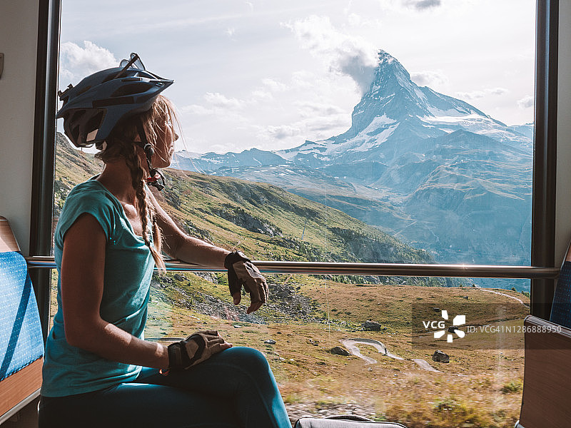 骑山地车的人望向阳光明媚的火车窗外，马特洪峰景色图片素材