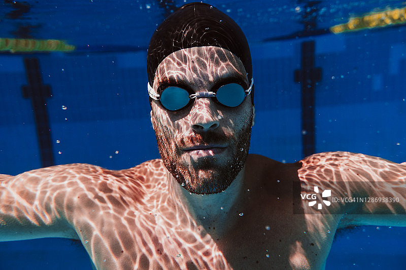 年轻的男性游泳运动员在游泳池水下游泳图片素材