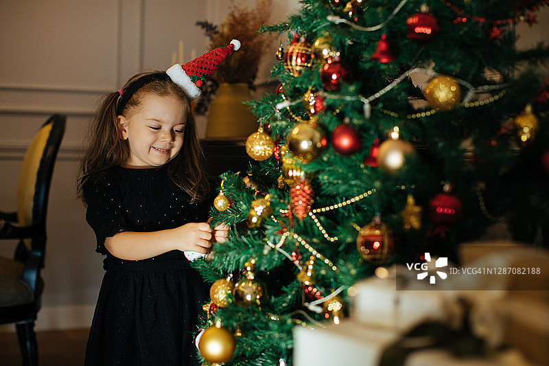 快乐的小女孩早上在圣诞树上带着礼物图片素材