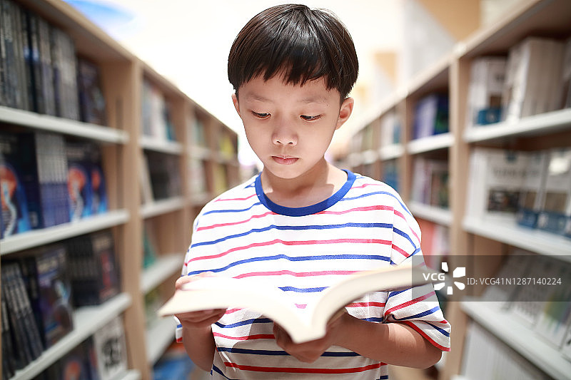 快乐的亚洲孩子在图书馆看书。图片素材