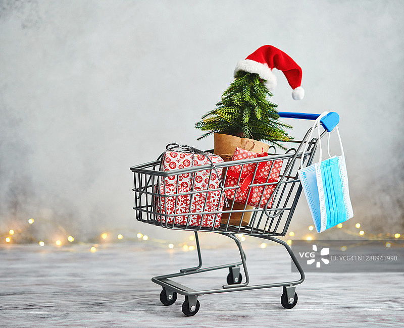 圣诞购物与COVID-19。购物车与保护面膜和礼物图片素材