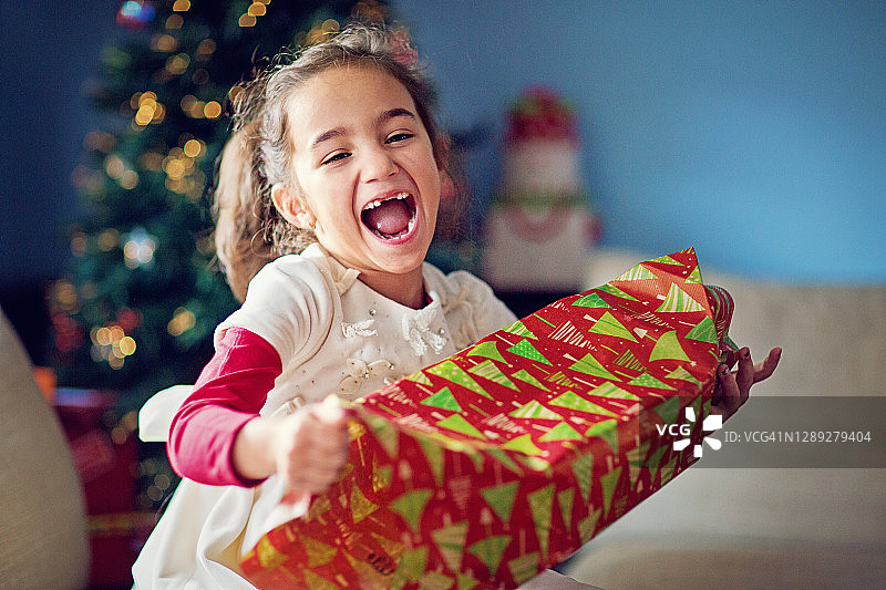快乐的女孩正在打开她的圣诞礼物图片素材