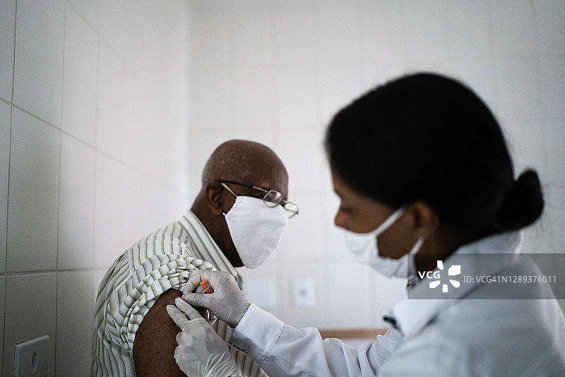 女医生给一个年长的病人注射疫苗图片素材