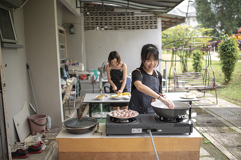 亚裔华人母亲和女儿在后院厨房准备食物。女儿在向母亲学习图片素材